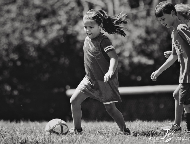 black and white photo of kids playing soccer in park